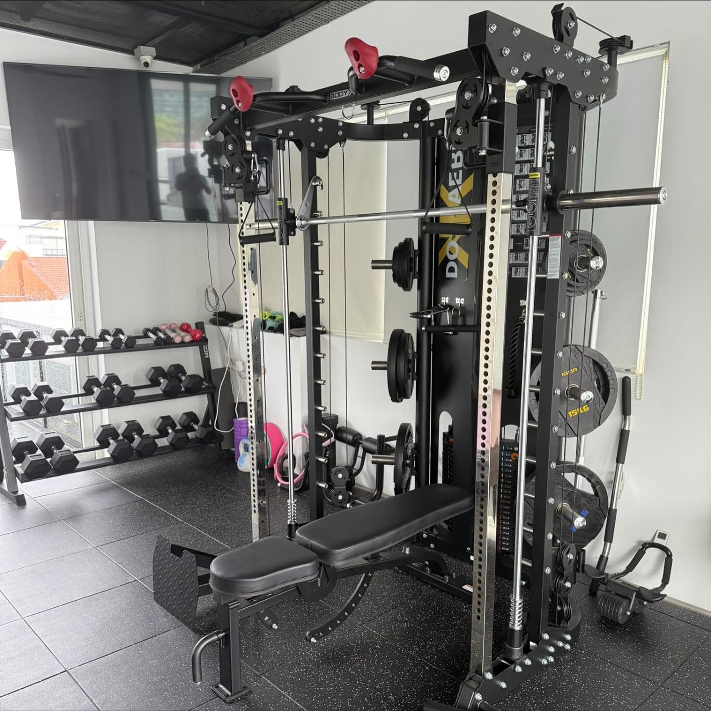 Home gym setup with Bodyx 3058 all in one trainer, dumbbells and bench.